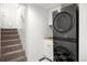 Modern laundry room featuring stacked washer and dryer, adjacent to the stairs at 5103 Quitman St, Denver, CO 80212