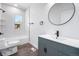 Updated bathroom featuring a sleek vanity, contemporary fixtures, a round mirror, and a bright window over the tub at 4745 N Clay St, Denver, CO 80211