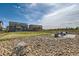 Expansive backyard view with grass, wooden fence and a fire pit under a cloudy blue sky at 38 Morgan Cir, Erie, CO 80516