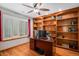 Home office boasts wood built-ins, hardwood flooring, a ceiling fan, and natural light at 9640 Moss Rose Cir, Highlands Ranch, CO 80129