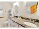 Bathroom featuring dual sinks with granite counters, white cabinets, and round mirrors at 9546 High Cliffe St, Highlands Ranch, CO 80129