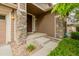 Close-up of a front porch with stone columns, a dark wood door, and lush landscaping at 3126 Aspen Creek Dr, Highlands Ranch, CO 80129