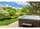 A bubbling hot tub situated on a brick patio with landscaping and a view of a golf course at 3126 Aspen Creek Dr, Highlands Ranch, CO 80129