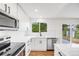 A bright kitchen featuring white cabinets, stainless steel appliances, hardwood floors and a window overlooking a yard at 12678 W Dorado Pl, Littleton, CO 80127