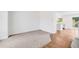 A well-lit living space featuring neutral carpet flowing into hardwood flooring and a view into the kitchen at 12678 W Dorado Pl, Littleton, CO 80127