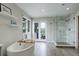 This modern bathroom features a luxurious soaking tub, a marble tiled glass shower, and backyard views at 11904 W Auburn Dr, Denver, CO 80228