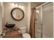 This bathroom features a vessel sink, toilet, frameless glass shower, and a round framed mirror with decorative lighting at 11904 W Auburn Dr, Denver, CO 80228