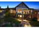 Backyard exterior view at dusk showing tiered landscaping, lighting, and covered deck access via stairway at 10687 Featherwalk Way, Highlands Ranch, CO 80126