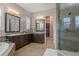 Elegant bathroom with double sinks, granite counters, a glass-enclosed shower, and a linen closet at 10687 Featherwalk Way, Highlands Ranch, CO 80126