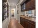 Hallway features hardwood floors, gray walls, decorative wall art, and a built-in bar area with granite countertops at 10687 Featherwalk Way, Highlands Ranch, CO 80126