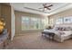 Spacious main bedroom with large windows, plantation shutters, tray ceilings, and neutral carpeting at 10687 Featherwalk Way, Highlands Ranch, CO 80126