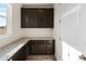 Butler's pantry with granite countertops, dark wood cabinets, and ample storage at 24325 E Ada Pl, Aurora, CO 80018