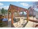 Relax in the backyard underneath a wooden gazebo with stylish patio furniture and a hot tub at 8280 Everett Way, Arvada, CO 80005