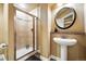 Bathroom featuring tiled shower, pedestal sink, and round mirror at 11985 Singing Winds St, Parker, CO 80138