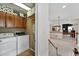 A functional laundry room with a modern washer and dryer, wooden cabinets and hall access at 11985 Singing Winds St, Parker, CO 80138