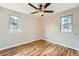 Bright bedroom featuring hardwood floors, a ceiling fan, and natural light from the two windows at 5235 Dover St, Arvada, CO 80002