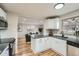 Open kitchen with white cabinets and stainless appliances overlooks the living room at 5235 Dover St, Arvada, CO 80002