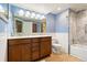 Well-lit bathroom features double sink vanity with wood cabinets and shower with patterned tile surround at 3461 Maple Cir, Brighton, CO 80601