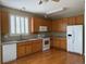 Bright kitchen featuring wooden cabinets, white appliances, a window with shutters, and hardwood flooring at 1216 S Flat Rock Cir, Aurora, CO 80018