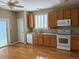 A well-lit kitchen featuring hardwood floors, wooden cabinetry, and appliances including an oven, and a dishwasher at 1216 S Flat Rock Cir, Aurora, CO 80018