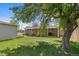 Green backyard with mature trees, with a view of the home's brick exterior and covered porch at 7736 Vallejo St, Denver, CO 80221