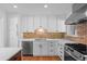 Modern kitchen showcasing white cabinets, brick backsplash, and stainless steel appliances at 7736 Vallejo St, Denver, CO 80221