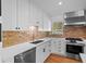 Modern kitchen showcasing white cabinets, brick backsplash, and stainless steel appliances at 7736 Vallejo St, Denver, CO 80221