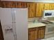 Kitchen featuring white appliances, including a refrigerator and microwave, complemented by wooden cabinetry at 2907 S Upham St, Denver, CO 80227