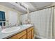 Bright bathroom featuring a double sink vanity with wood cabinets and a shower with a striped curtain at 9023 Apache Plume Dr # C, Parker, CO 80134
