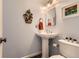 Stylish powder room featuring a pedestal sink, decorative mirror, and light blue walls at 5 Cliffrose, Littleton, CO 80127