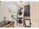 Laundry room featuring a stainless steel stacked washer and dryer and a utility sink at 5 Cliffrose, Littleton, CO 80127