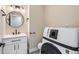 Modern bathroom with a round mirror, sleek vanity, and updated washer/dryer at 2888 S Fundy St, Aurora, CO 80013