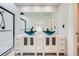 Modern bathroom with dual blue vessel sinks, large mirror, white marble tile, and black shower hardware at 2685 S Dayton Way # 67, Denver, CO 80231