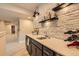 Basement bar with stylish brick wall, open shelves, quartz countertops and black cabinetry at 1766 Summerglow Ln, Monument, CO 80132