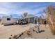 Wide exterior view showcasing the Quonset-style garage, recreational vehicles, and artistic landscaping at 410 Goodrich Ave, Platteville, CO 80651