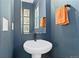 Cozy powder room features a pedestal sink, framed mirror, and blue accent wall at 20998 E 60Th Pl, Aurora, CO 80019