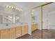 Bathroom featuring double sinks with wooden cabinets, tile floors and a large, mirrored closet at 17303 E Dewberry Cir, Parker, CO 80134