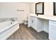 Bathroom featuring a modern vanity, a large mirror, and soaking tub with marble tile surround at 12024 W Cross Dr # 106, Littleton, CO 80127