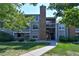 Exterior view of a well-maintained multi-story apartment building with landscaped grounds and a brick chimney at 12024 W Cross Dr # 106, Littleton, CO 80127