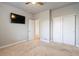 A carpeted bedroom with ceiling fan, closet with sliding doors, TV, and entry into another room at 7207 S Scottsburg Way, Aurora, CO 80016