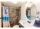 Modern bathroom with a stylish vanity, round mirror, and tiled shower with glass doors at 10538 Quivas St, Northglenn, CO 80234