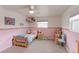 Cozy ' bedroom with pink walls, carpeted floors, and a window letting in natural light at 10538 Quivas St, Northglenn, CO 80234