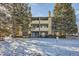 Multi-story building with balconies and mature trees in a snowy landscape at 16051 E Alaska Pl # 4, Aurora, CO 80017