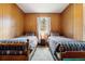 Cozy bedroom featuring two twin beds, wood-paneled walls, and plush carpet at 17422 N Canyon Rd, Littleton, CO 80127