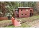 Charming cabin-style home featuring a red-toned exterior and surrounded by lush greenery and mature trees at 17422 N Canyon Rd, Littleton, CO 80127