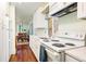 Bright galley kitchen with white appliances and cabinets, and dark wood flooring at 17422 N Canyon Rd, Littleton, CO 80127