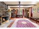 Cozy living room featuring a stone fireplace, wooden beams, and large area rug perfect for relaxing or entertaining at 17422 N Canyon Rd, Littleton, CO 80127