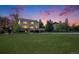 Spacious backyard featuring a large lawn, wood deck, and mature trees at sunset at 7624 Russell Ct, Arvada, CO 80007