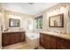 Bright bathroom featuring double vanities with dark wood cabinets and a relaxing soaking tub under a window at 7624 Russell Ct, Arvada, CO 80007