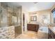 Beautiful bathroom with stone-look tile, a glass-enclosed shower, and a soaking tub surrounded by similar stone-look tile at 7624 Russell Ct, Arvada, CO 80007